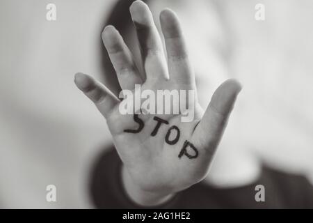 Little frightened girl shows the word Stop written on the arm. Children are subjected to violence and publishing in the home and school concept and Stock Photo