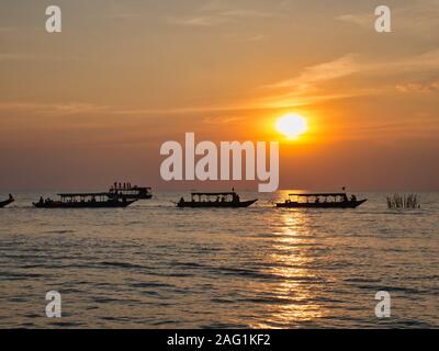 Tourists enjoy the sunset in boats on Tonle Sap Lake, near Siem Reap in Cambodia. Stock Photo