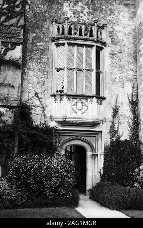 Lacock Abbey, Lacock, Wiltshire, England, UK: south elevation with old door to the cloisters and mullioned window above: the window featured in Henry Fox Talbot's ground-breaking first negative photograph of 1835.  Old black and white film photograph Stock Photo