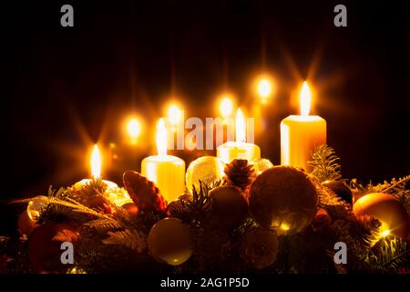 Christmas wreath with four burning yellow candles, advent time, christmas eve, black background, copy space Stock Photo