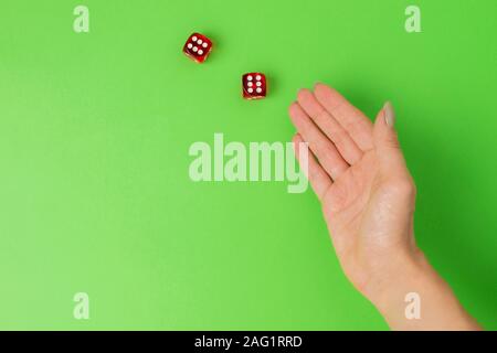 female hand rolling red dice isolated on green background. Stock Photo