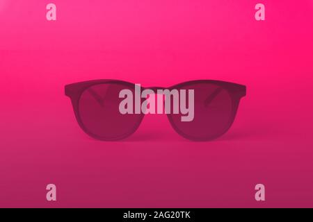 Vintage sunglasses in pink lighting. Pink suglasses in minimal and summer concept background. Stock Photo