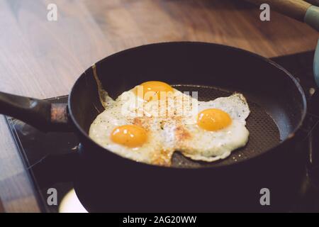 Fried eggs in the pan for breakfast. Cooking breakfast with fried eggs and toast in the kitchen. Stock Photo