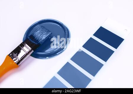 Brush and an open can with blue on a plain gray background Stock Photo