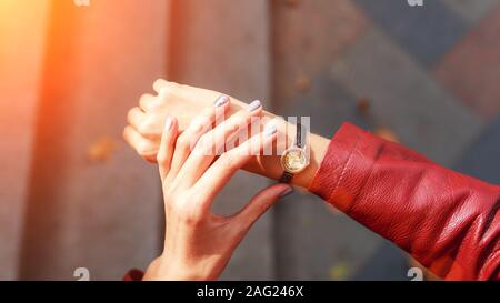 street style fashion details. close up, young fashion blogger wearing a jacket and a analog wrist watch. stylish woman checking the time on her watch. autumn fall season. Stock Photo