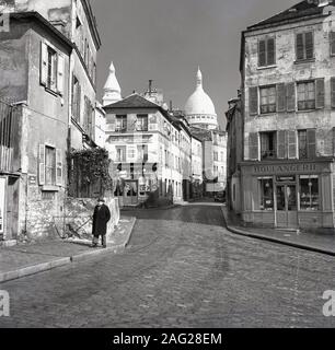 1950s, historical, a view of Le Consulat restuarant, 18 Rue Norvins, Paris, France, an historic cafe on a cobbled lane in the centre of Montmartre, the artistic district of the city. The famous domes of the Notre Dame cathedral can be seen in the distance. Stock Photo