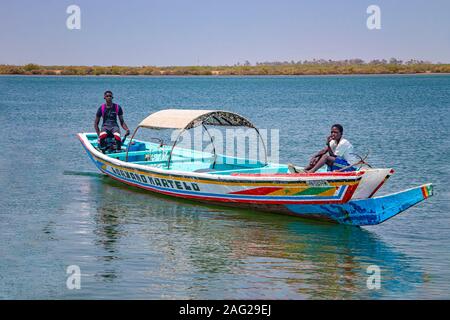 Somone lagoon, Senegal- April 26 2019: Two boys are sailing on a typical wooden colorful canoe in Senegal, Africa. Stock Photo