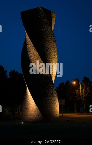 modern architecture at night in the form of a helix made from bricks. The wall is illuminated by light beams, causing a scenic textured effect. Stock Photo