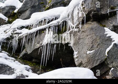 Horizontal close-up of icicles on rock near a waterfall. Stock Photo