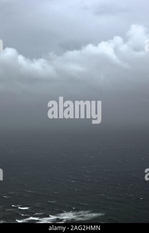 Overcast, heavy sky looming over a dark, agitated sea. Stock Photo