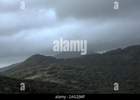 Overcast, heavy sky looming over dark mountains in Italy. Stock Photo