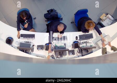 Three customer service agents working at a help desk at the airport. Stock Photo