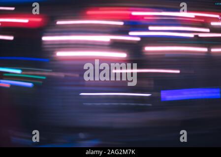 Defocused neon streaks blurred in motion in the dark of the night. Riding or driving a vehicle in the night city. Purple urban abstract. Stock Photo