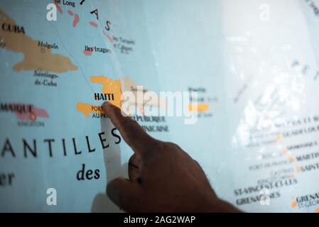 A closeup shot of a person pointing to Haiti on the map Stock Photo