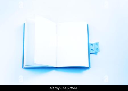 Still life, business, office supplies or education school concept: open bright blue notebook on white background. Copy space, flat lay. Classic Blue color 2020 inscription. Stock Photo