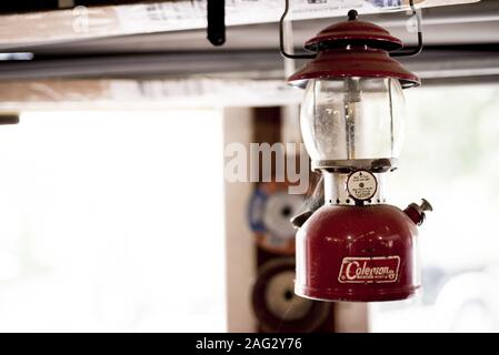 JACKSON, UNITED STATES - Jan 01, 2019: Old Colman lamp hanging in a garage. The window is seen behind a little blurred out. Stock Photo