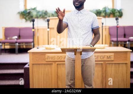 Male standing and reading the bible on a wooden stand in a church Stock Photo