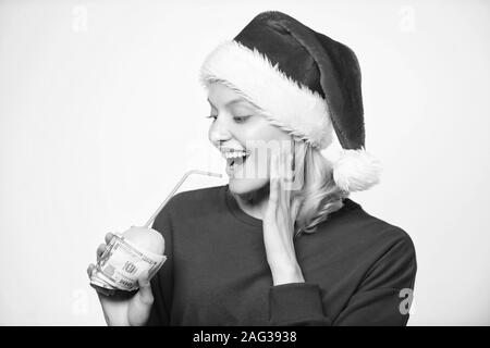 Girl santa hat drink juice lemon wrapped in banknote. Totally natural lemon juice. Fresh lemonade drink with straw. Symbol of wealth and richness. Girl with lemon and money. Lemon money concept. Stock Photo