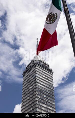 Vertical shot of the flag of Mexico waving over a high rise building Stock Photo