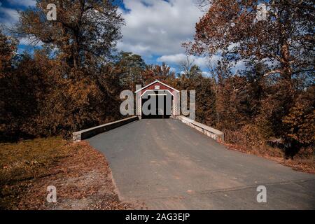 A horizontal shot of a cover bridge in the forest surrounded by beautiful trees under the breathtaking clouds Stock Photo