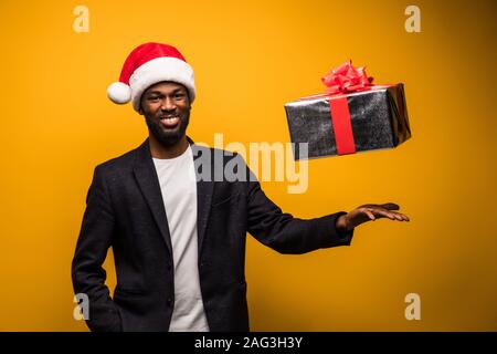 African American man in Santa hat throwing up gift box isolated Stock Photo