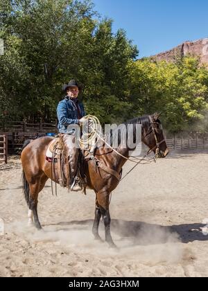 A cowboy wrangler with his lariat on a ranch near Moab, Utah.  He wears leather chaps to protect his legs from thorny brush while riding the range. Stock Photo