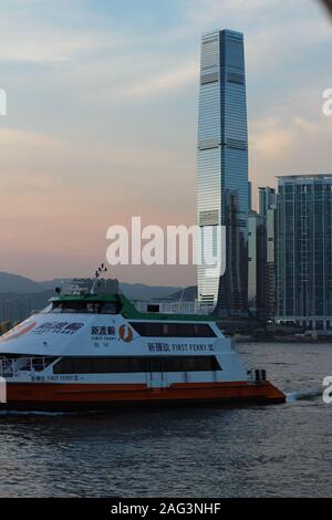 Vertical shot of a sailing boat with beautiful buildings in the background taken in Hong Kong Stock Photo