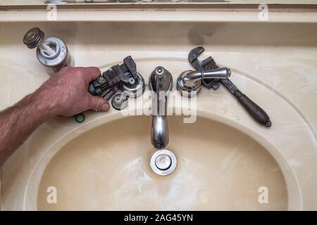 A photo looking down on a broken faucet with a man working on it. Great for a plumbing or handyman ad. Stock Photo