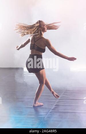 Beautiful Young modern female dancer dancing in the studio. Sport, dancing and urban culture concept. Young female dancer performing on the stage. Eff Stock Photo