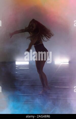 Beautiful Young modern female dancer dancing in the studio. Sport, dancing and urban culture concept. Young female dancer performing on the stage. Eff Stock Photo