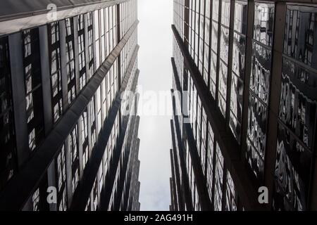 Low angle greyscale shot of two identical buildings and a line of the sky above Stock Photo