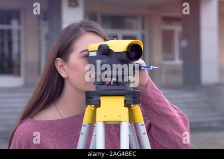 Young female engineer is measuring the distance on the road with the Telescope camera. During construction preparation or road maintenance in construc Stock Photo
