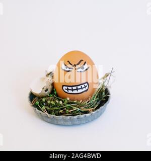 Depiction of an angry face on an egg in a cute small plate on a white background Stock Photo