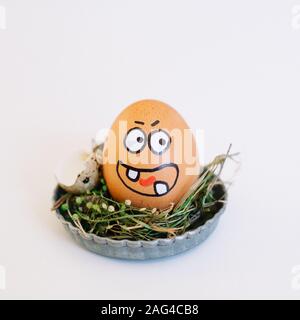 Depiction of an angry face on an egg in a cute small plate on a white background Stock Photo