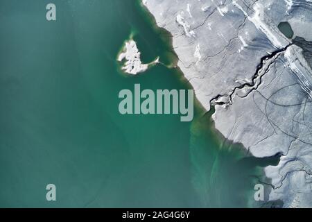 High angle shot of a big crack on the stony shore next to the turquoise water Stock Photo