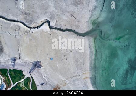 High angle shot of a big crack on the stony shore next to the turquoise water Stock Photo