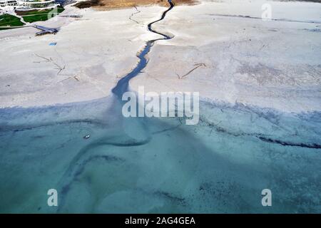 High angle shot of a big crack on the stony shore next to the turquoise water Stock Photo