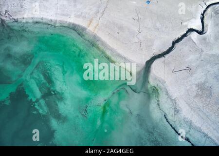 High angle shot of a big crack on the stony shore next to the turquoise water Stock Photo