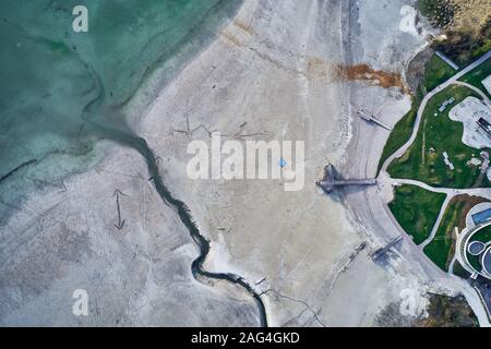 High angle shot of a big crack on the stony shore next to the turquoise water Stock Photo