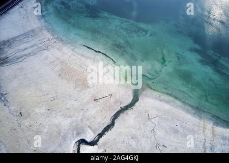 High angle shot of a big crack on the stony shore next to the turquoise water Stock Photo