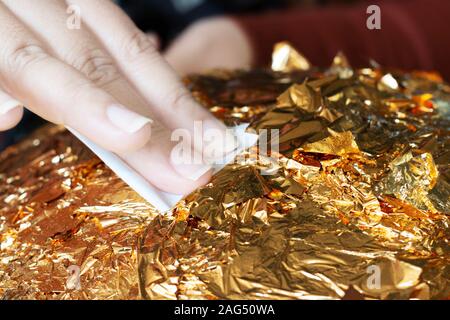 hand of buddhist gilding gold leaflet on golden ball in temple to worship buddha