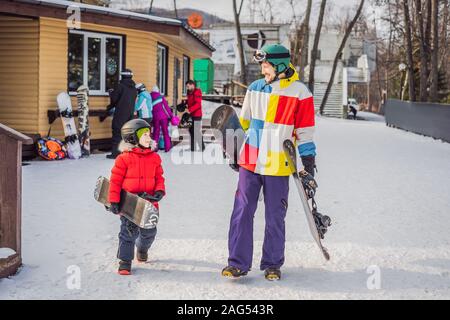 Snowboard instructor teaches a boy to snowboarding. Activities for children in winter. Children's winter sport. Lifestyle Stock Photo