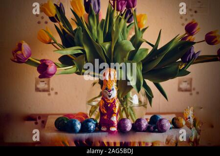 Closeup shot of bunny chocolate near easter eggs and flowers with a blurred background Stock Photo