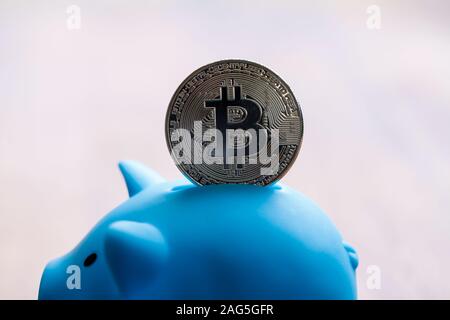 Large Bitcoin being deposited into a piggy bank Stock Photo