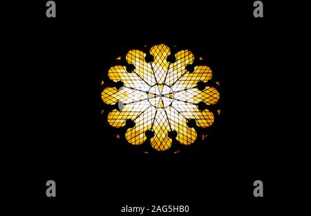 Closeup shot of a beautiful flower-shaped yellow vitrage window on black background Stock Photo