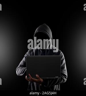 Cybercrime, hacking and technology crime. no face hacker with laptop on black background with clipping path. Stock Photo