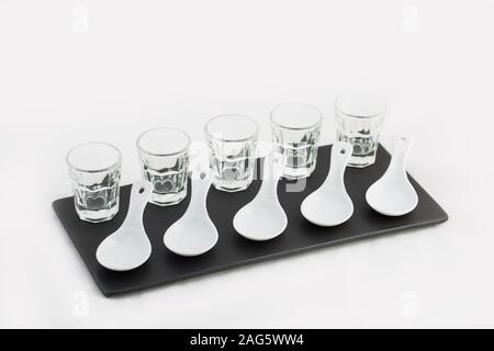 Black ceramic tray with five whiskey cups and spoon-shaped plates isolated on a white background Stock Photo