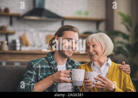 In the morning. Grey-haired elderly woman having morning coffee with son Stock Photo