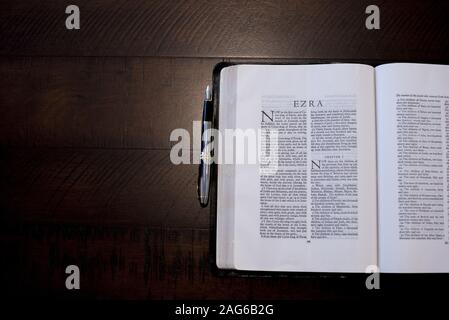 Overhead shot of an open bible near a fountain pen on a wooden surface Stock Photo