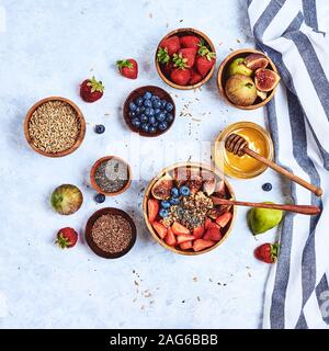 Healthy breakfast and breakfast ingredients, oatmeal with fruits and berries, figs, blueberries, strawberries, flax and chia seeds, honey. Top view Stock Photo